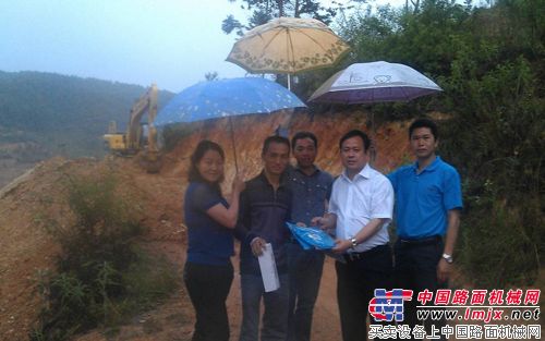玉柴重工副总经理陈德坚（右二）在雨中为挖掘机用户送上服务月礼品